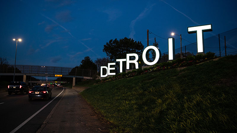 The new Detroit sign along I-94 lit up at night, spelling D E T R O I T