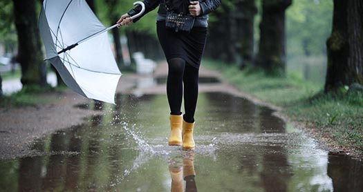 a person runs through a puddle wearing yellow rain boots
