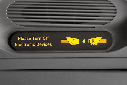 a sign on an airplane is lit up, asking you to please turn off electronic devices