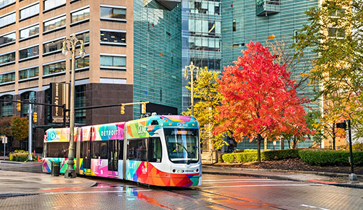 City tram in Downtown Detroit, colorful fall foliage in the background