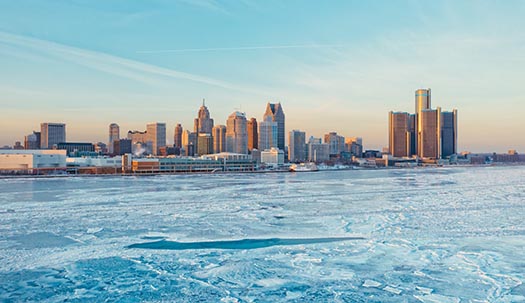 a view across the frozen river at the wintry skyline of Detroit