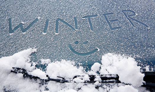 a smiley face and the word winter are drawn in the snow on a car windshield